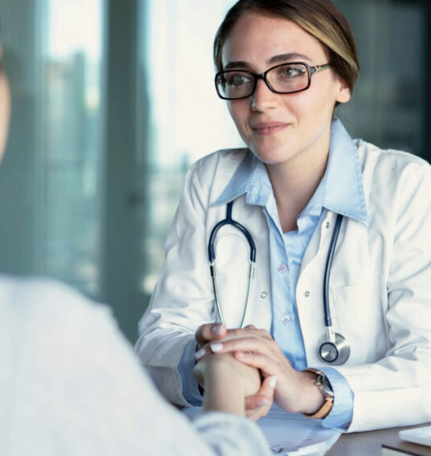 a doctor holds a patient’s hands, comforting them through schizophrenia struggles